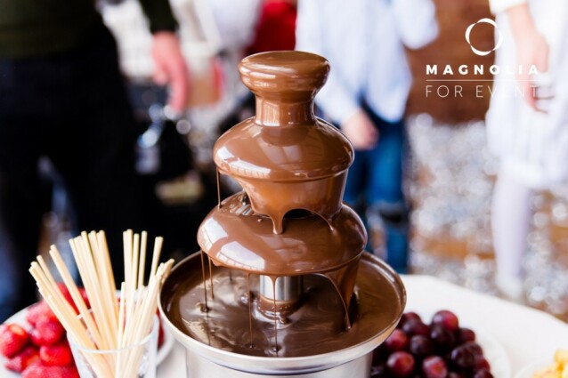 Vibrant Picture of Chocolate Fountain Fontain on childen kids birthday party with a kids playing around and marshmallows and fruits dip dipping into fountain