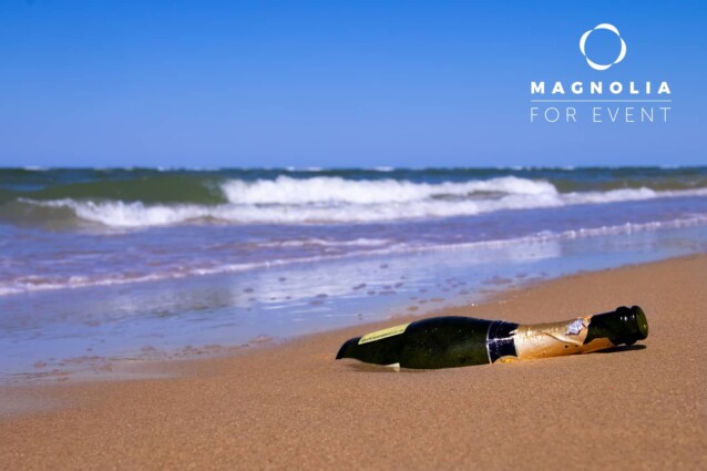 Ocean beach with empty bottle of champagne which was taken to the shore by a storm, concept secret message